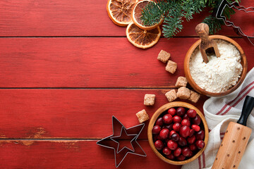 Christmas culinary background with ingredients for cooking christmas baking cranberries, sugar, cinnamon and Christmas tree branches on rustic old red wooden table background.Top view copy space.