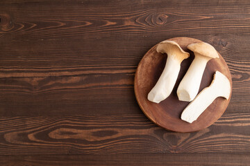 King Oyster mushrooms or Eringi (Pleurotus eryngii) on brown wooden. Top view, copy space.