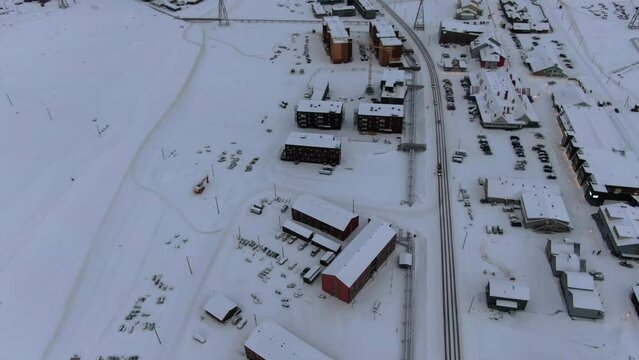 Drone view in Svalbard flying over Longyearbyen town showing houses in a snowy area with card on a road top view in Norway