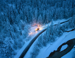 Aerial view of mountain road in fairy forest in snow and snowplow clears the snow off a road at...