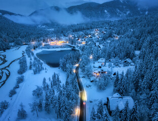 Aerial view of fairy alpine village in snow, road, forest, Jasna lake, houses, street lights at...