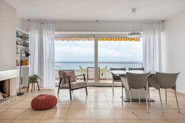 Table and soft armchair near terrace with panoramic window