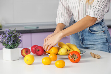 Organic food. Woman puts fruit on plate in kitchen. Diet and healthy eating concept.