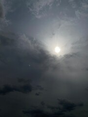 Dark and grey clouds in the overcast sky, sun shining through the clouds