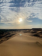 Sun shining through the clouds and the blue sky over the mountains in the desert