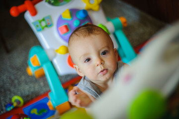 High-angle portrait of a toddler with conjunctivitis among his toys, looking at the camera.