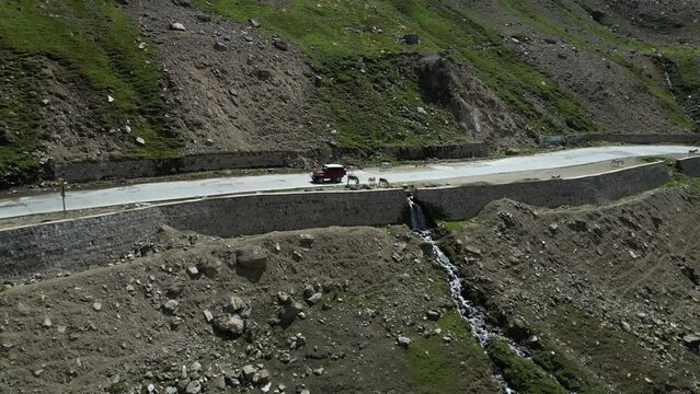 Aerial shot of jeep crossing donkeys on highway near lulus lake. Lulusar, or Lalusar, is a group of mountain peaks and a lake in the Kaghan Valley in the Khyber-Pakhtunkhwa province of Pakistan.