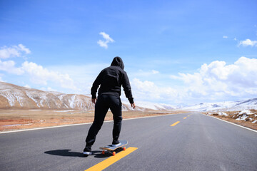 Skateboarder skateboarding on snowy country road