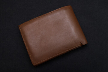 Top view of new brown genuine leather wallet isolated on black background.