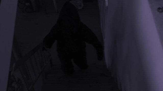 A scary amateur video of a man or a maniac with a knife, or an ax man climbing the steps in the dark. Horror, mysticism, crime, murderer.