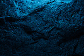 Black stone texture in blue neon lighting, dark abstract background. Natural mineral rock close up details, empty backdrop with copy space for design