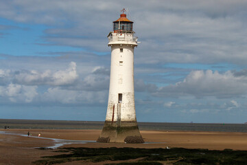 An historic Lighthouse on the beach with the sea in the background.