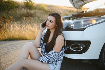 Young sexy woman with broken car calling on the cell phone.