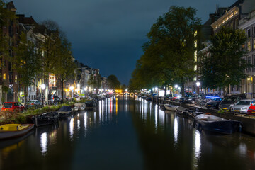 Fototapeta na wymiar Amsterdam Canal at Night and Parked Boats and Cars