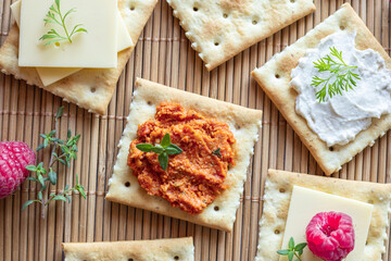 Various kind of salty crackers with vegan meat and vegan cream cheese decorated with fresh herbs and raspberries. Vegan food concept.