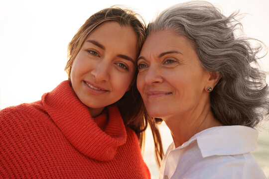 Smiling mother and daughter in front of sky
