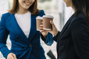 female colleague of half Asian descent holds a cup of coffee and smiles happily.