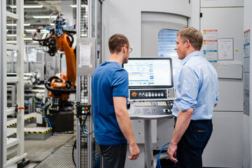 Businessman and employee standing at control panel in a factory