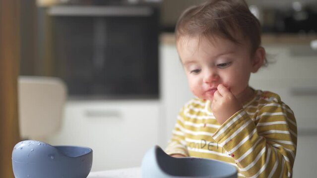 grimy baby eats with her hands from a plate. development of fine motor skills family kid dream concept. funny video baby dirty eats food from a plate with his lifestyle hands. dirty baby eats