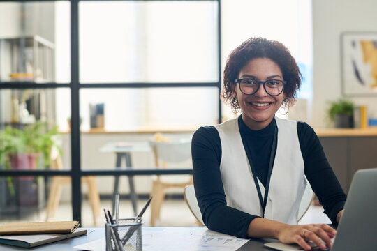 Happy Young Businesswoman Sitting With Laptop At Desk