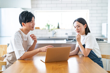 パソコンを見ながら話をするエプロンをつけた男女
