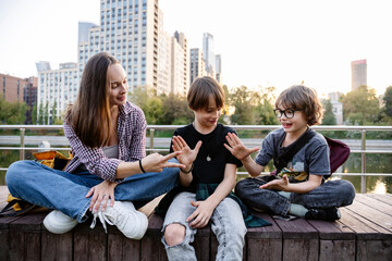 Happy mother playing with sons sitting on bench