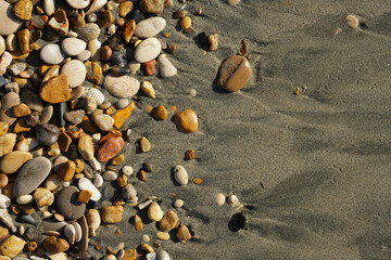 Pebbles on the seashore in close-up. A rocky beach. Rocks and sand in close-up. The natural background. Winter by the sea in the Mediterranean 