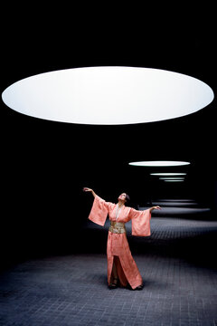 Woman wearing kimono and looking up at spotlight