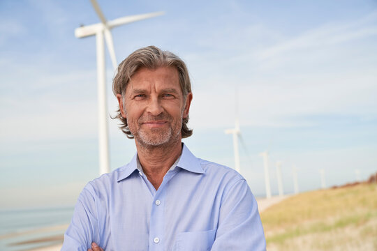 Smiling senior businessman in front of wind turbines