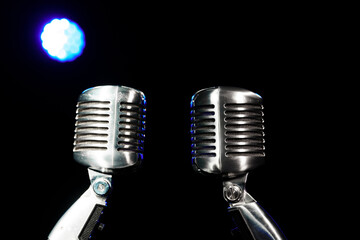Two metal retro microphones on a stand against the background of concert light.
