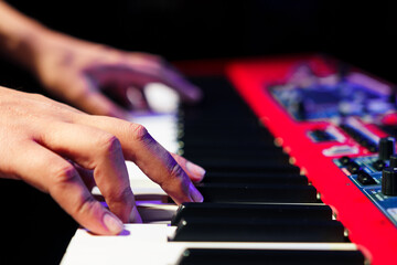 Close-up of a pianist's hands on an electronic synthesizer.