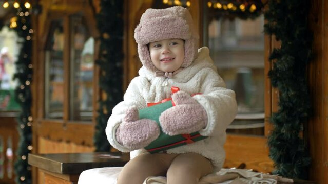 Little girl at the Christmas market. The child is holding a box with a present in her hand.