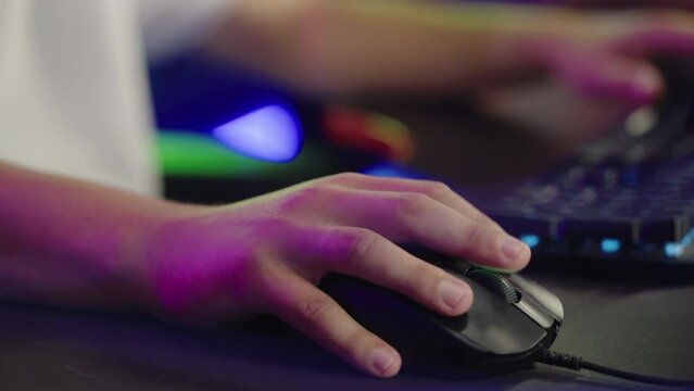 Close-up of a person using a gaming mouse at the computer club. A Player is pressing the buttons on the gaming mouse. Male hand is scrolling the wheel on the gaming mouse. Cyberclub. Peripheral device