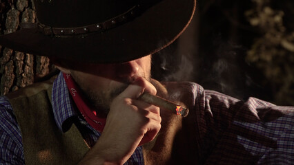 Cowboy with a cigar in the forest at night