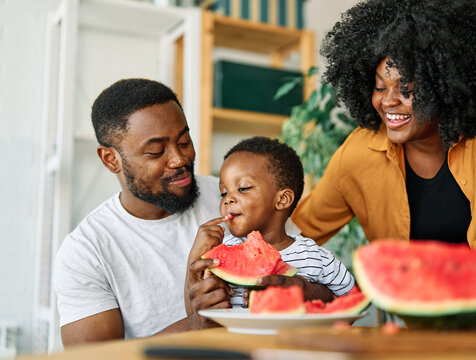child family kitchen food boy son father mother watermelon fruit slice summer organic meal fun preparing healthy diet eating home black - Powered by Adobe