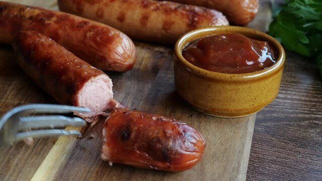 Grilled sausages Bockwurst on a wooden board. Break and pricked sausage with a fork. Close up