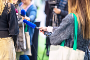 News, press conference or media scrum, female journalist holding microphone, other reporters and...