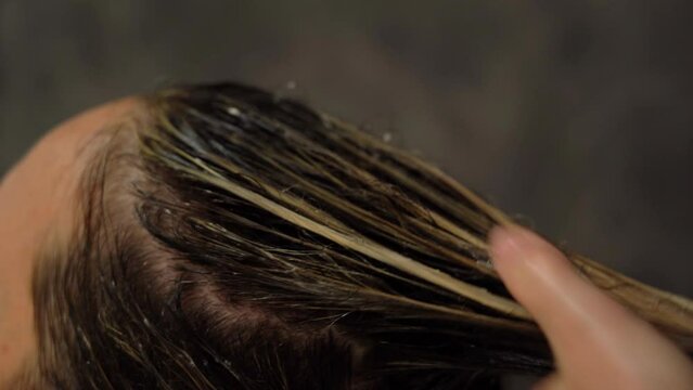 Professional hairdresser moisturizes hair with hair care cream oil