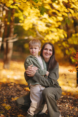 Fototapeta premium Mom and children walk in the park and enjoy the beautiful autumn nature. Happy family on an autumn walk. Natural Park. Family active holiday concept.