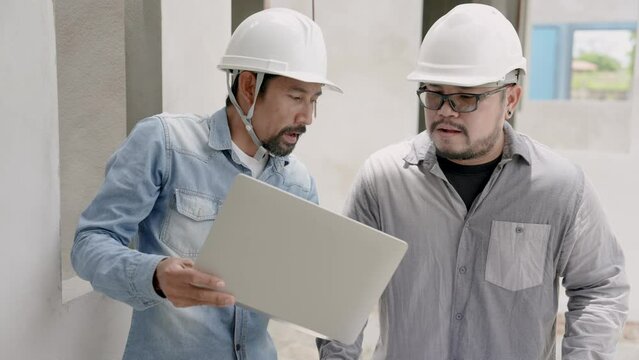 Engineer team discuss about stringer construction. Asian construction men in white helmets explain building plan, home design. On-site serious workers concern about the safety ceiling. Teamwork