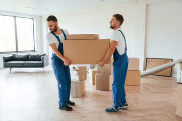 Fototapeta na wymiar One big heavy box. Two moving service employees in a room