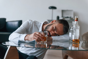 Life crisis. With whiskey. Upset young man drinker alcoholic is indoors