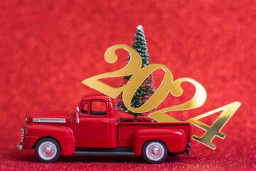 Decorative sign New Year 2024 on a red toy pickup truck, Christmas decor, selective focus
