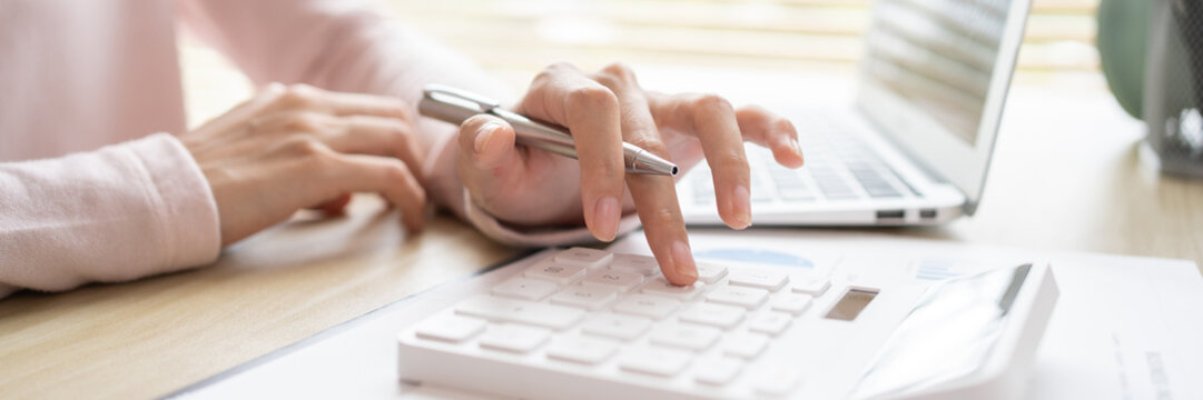 Close-up of hand pressing calculator to calculate income tax and company income in private office, Finance, Accounting, Tex, Statistical graphs of investing in real estate.