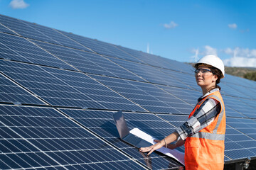 Young engineer inspect installation of solar panels installed check  with blueprint on the field,...