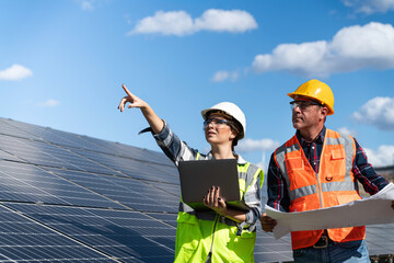 Young engineer inspect installation of solar panels installed check  with blueprint on the field, with recording inspection data on pc.
