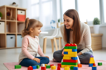 Happy mother and little girl playing with blocks on the floor.