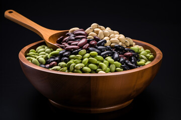 Mix organic legumes (soybean, red beans, green mung bean and black gram) in a wooden bowl, isolated on a dark background.