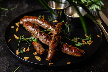 Grilled sausage on a dark plate with sauce