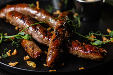 Grilled sausage on a dark plate with sauce